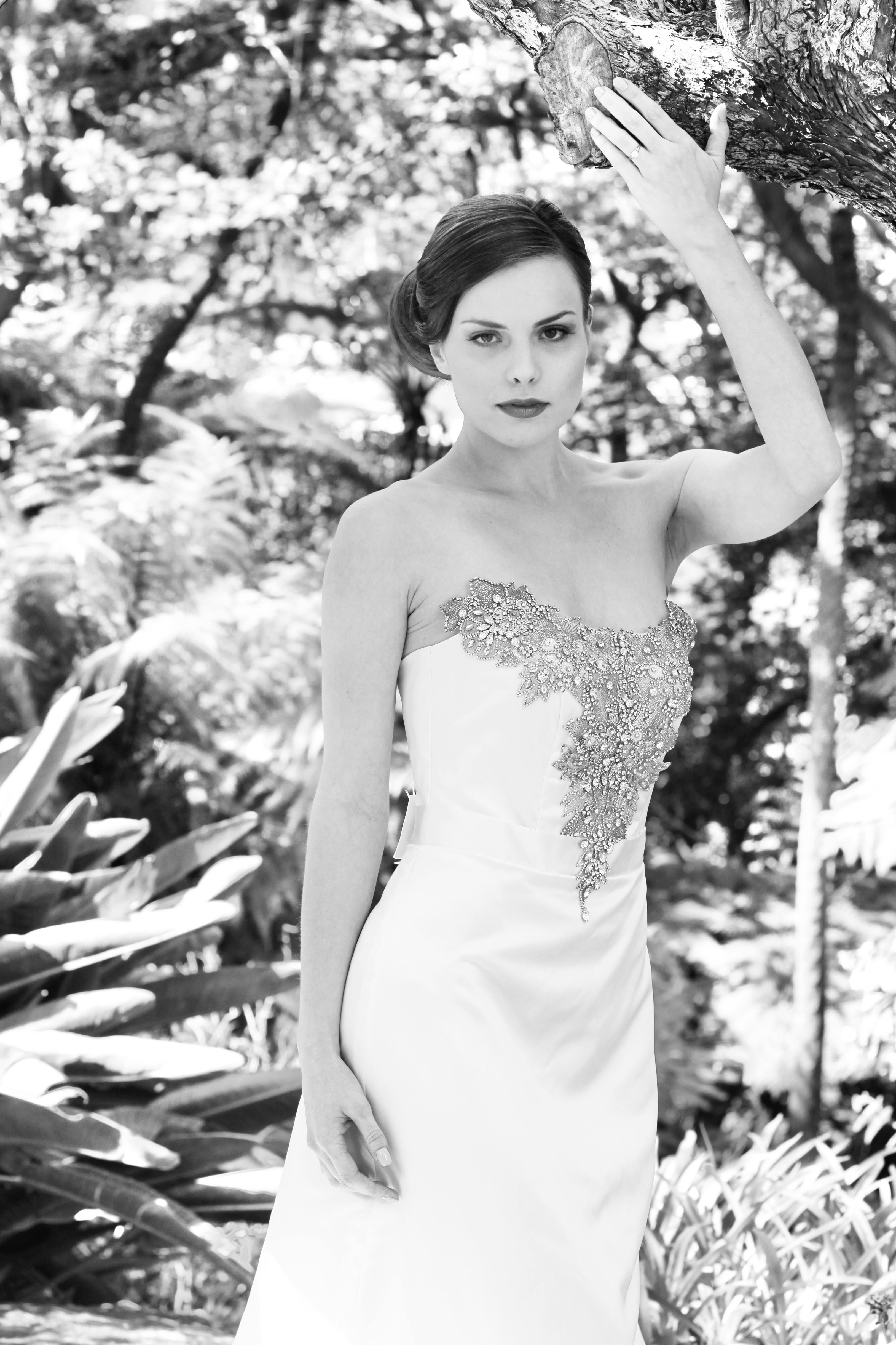 Stunning bride in a strapless gown poses elegantly outdoors.