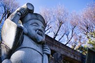Concrete Statue and Bare Trees Under a Blue Sky