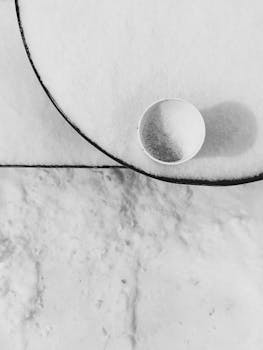 Abstract minimalist snow scene with a lone white cup creating contrast and shadow.