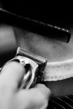 Detailed shot of a barber using clippers and comb during a haircut.