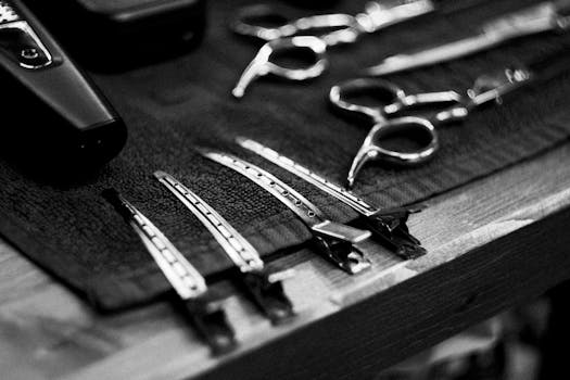 Close-up of barber tools on a towel in black and white, highlighting scissors and hair clips.