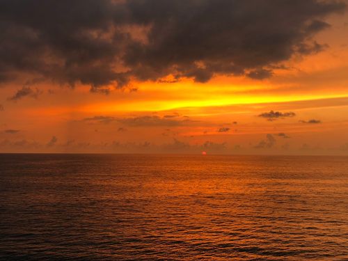 Free Mesmerizing sunset over the ocean with dark dramatic clouds creating a stunning sky view. Stock Photo