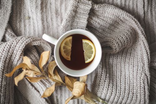 Free A warm cup of tea with lemon slices on a soft knit blanket, exemplifying cozy comfort. Stock Photo