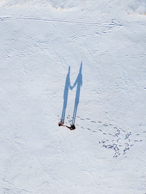 Shadow of Couple Holding Hands and Standing on a Snow 