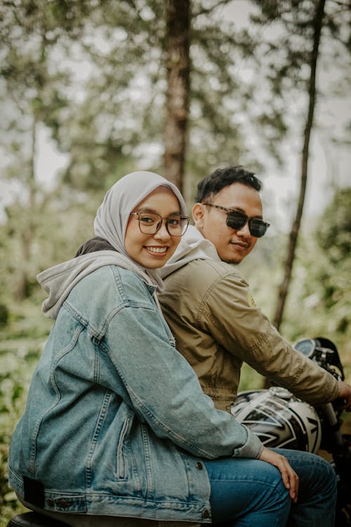 Smiling Couple on Motorcycle near Trees
