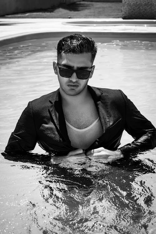Grayscale Photo of Man in Suit Jacket With Sunglasses on Water 