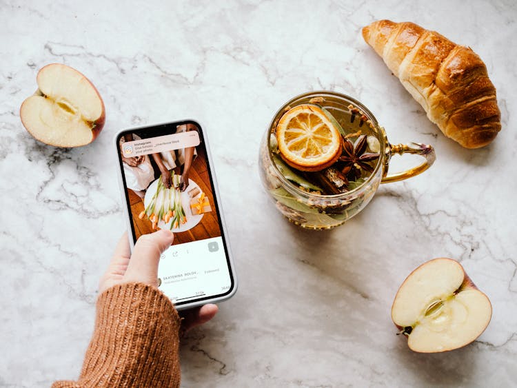 Woman Taking Photo With Her Phone Of Green Tea With Lemon 