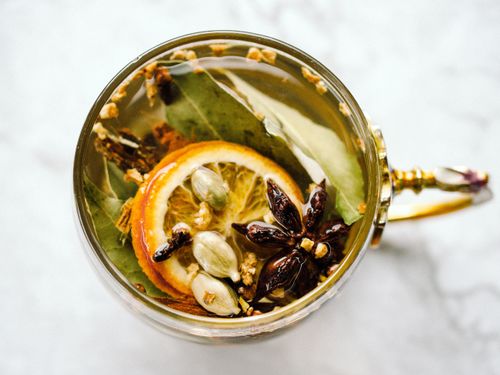 Free A top-view of herbal tea with citrus slices, star anise, and cardamom in an ornate cup. Stock Photo
