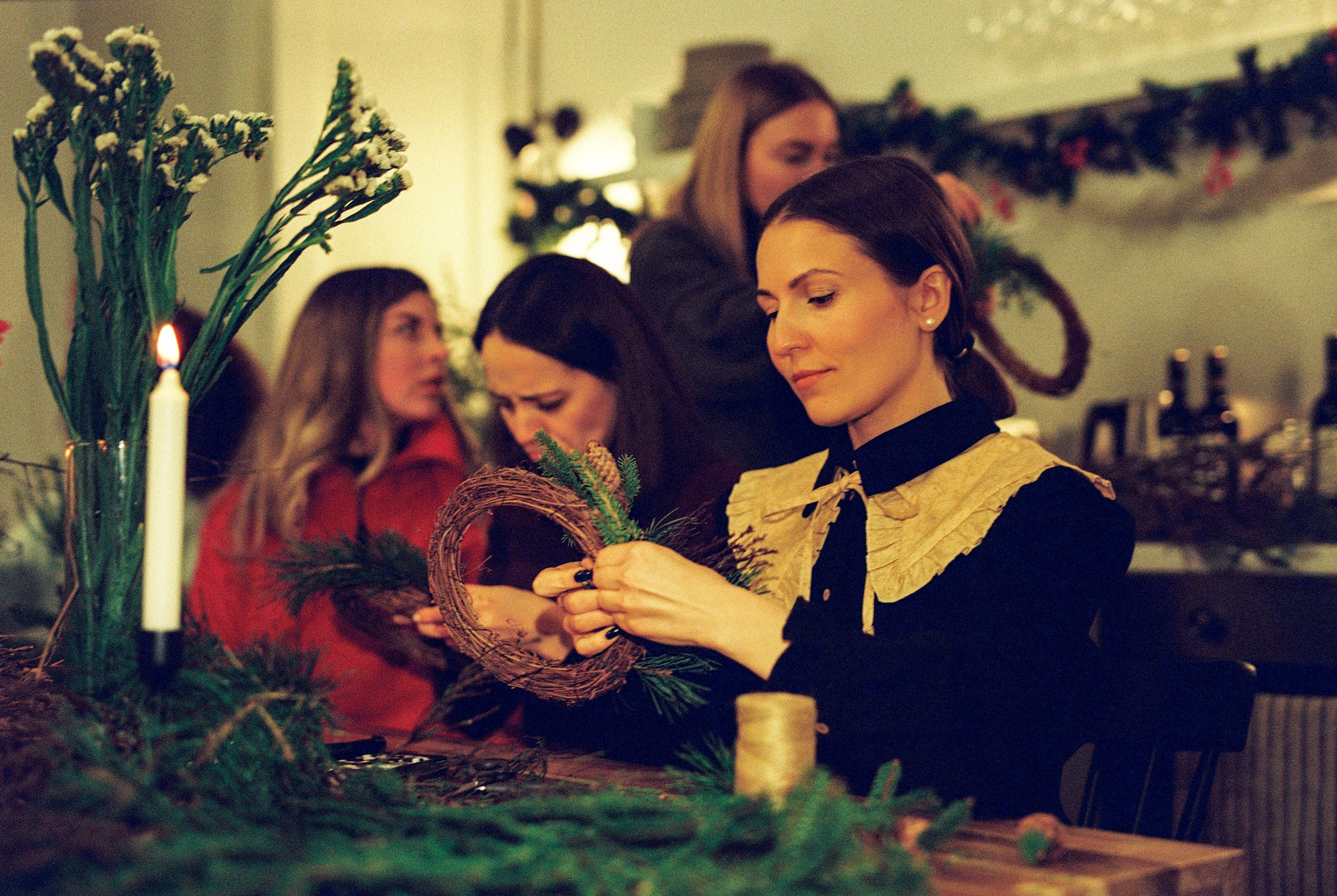 Women in a cozy indoor setting create festive Christmas wreaths. Holiday spirit.