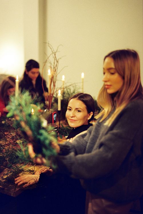 Free Women crafting wreaths in a cozy indoor Christmas workshop setting. Stock Photo