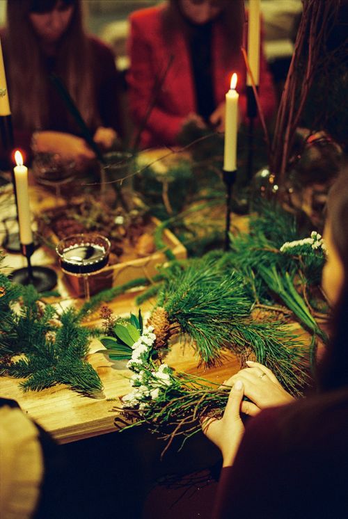 Free Festive gathering making Christmas wreaths with candles and wine. Stock Photo