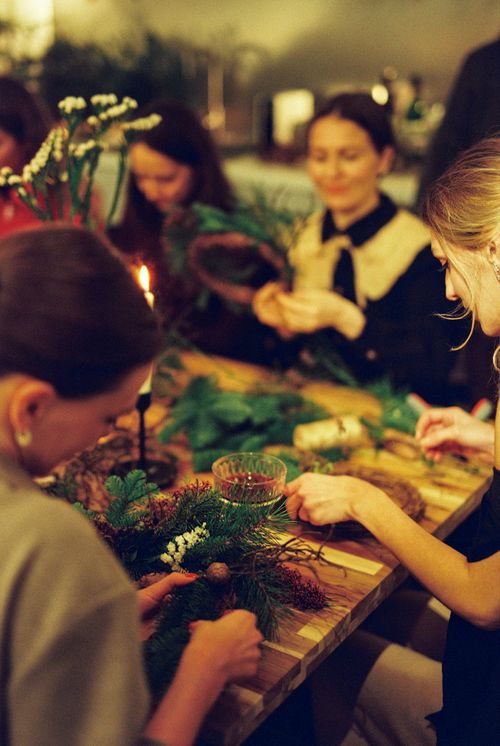 Free A group of women creating decorative wreaths indoors, evoking a festive holiday spirit. Stock Photo
