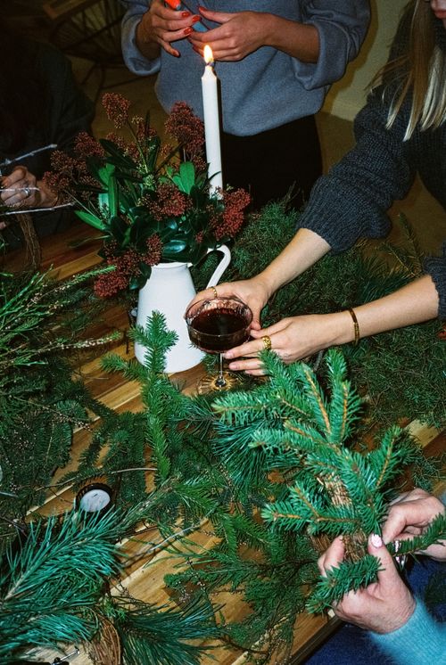 Free Hands arranging festive pine branches with a candlelit ambiance, evoking holiday warmth. Stock Photo