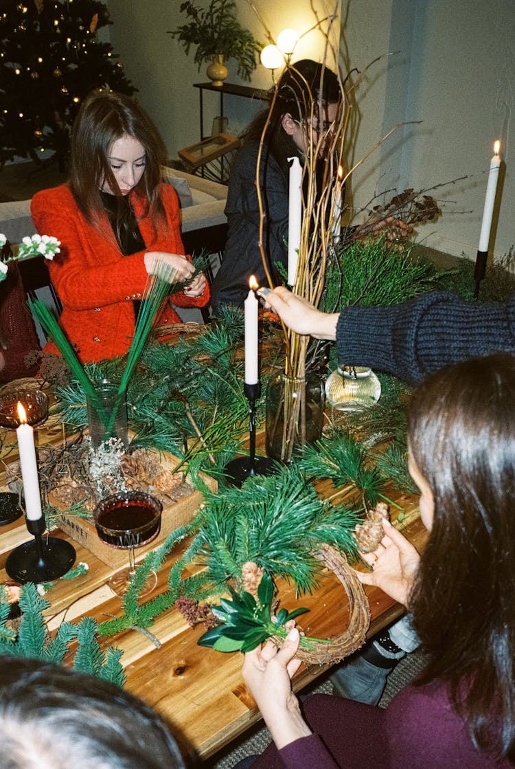 Busy Women Making Christmas Wreaths On The Wooden Table