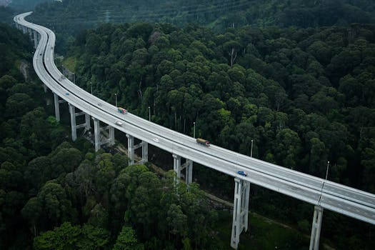Aerial drone shot of a highway cutting through dense forest in Rawang, Malaysia.