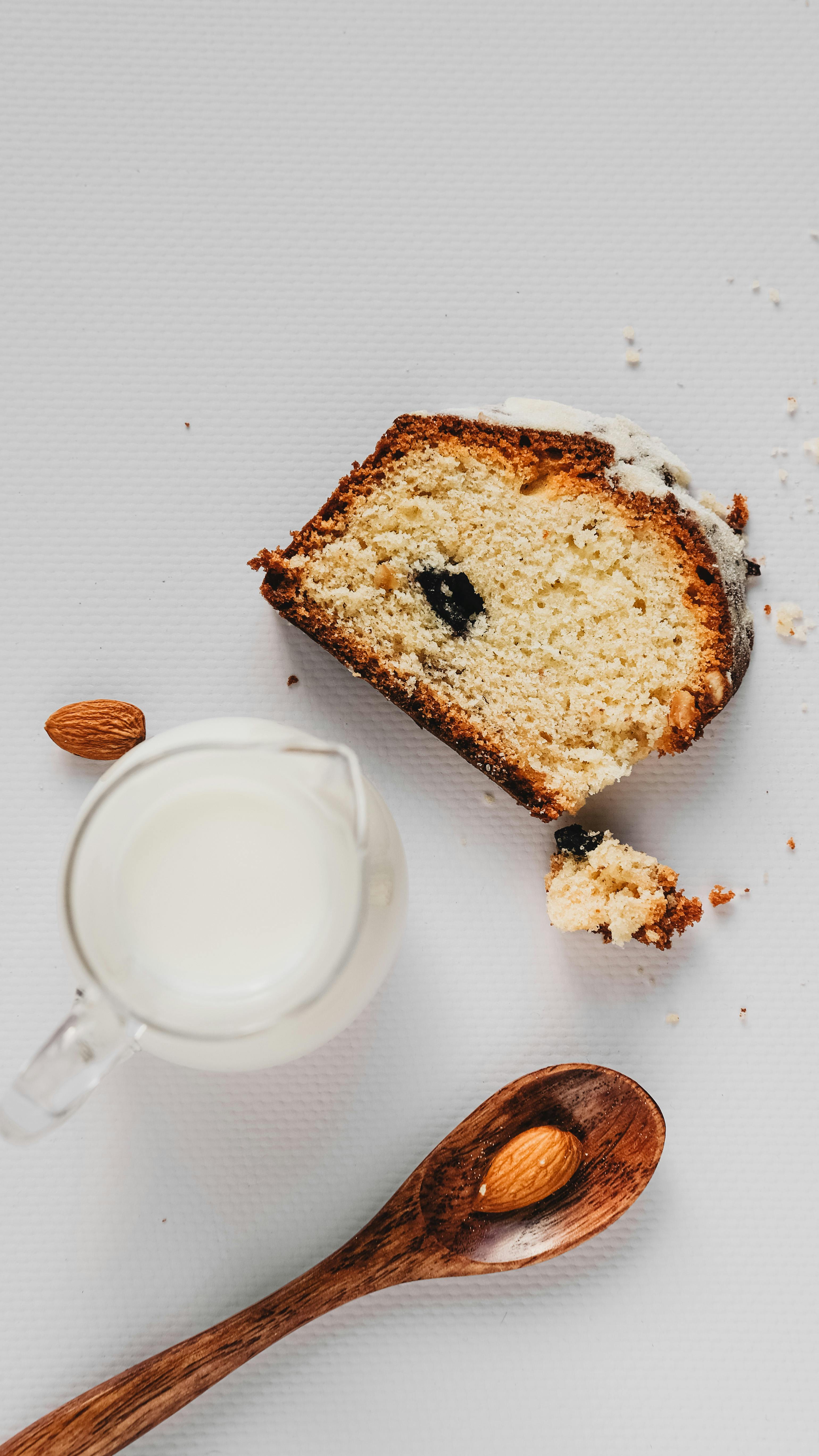 Close-up of a cake slice with almonds and a jug of milk, showcasing a cozy baking scene.