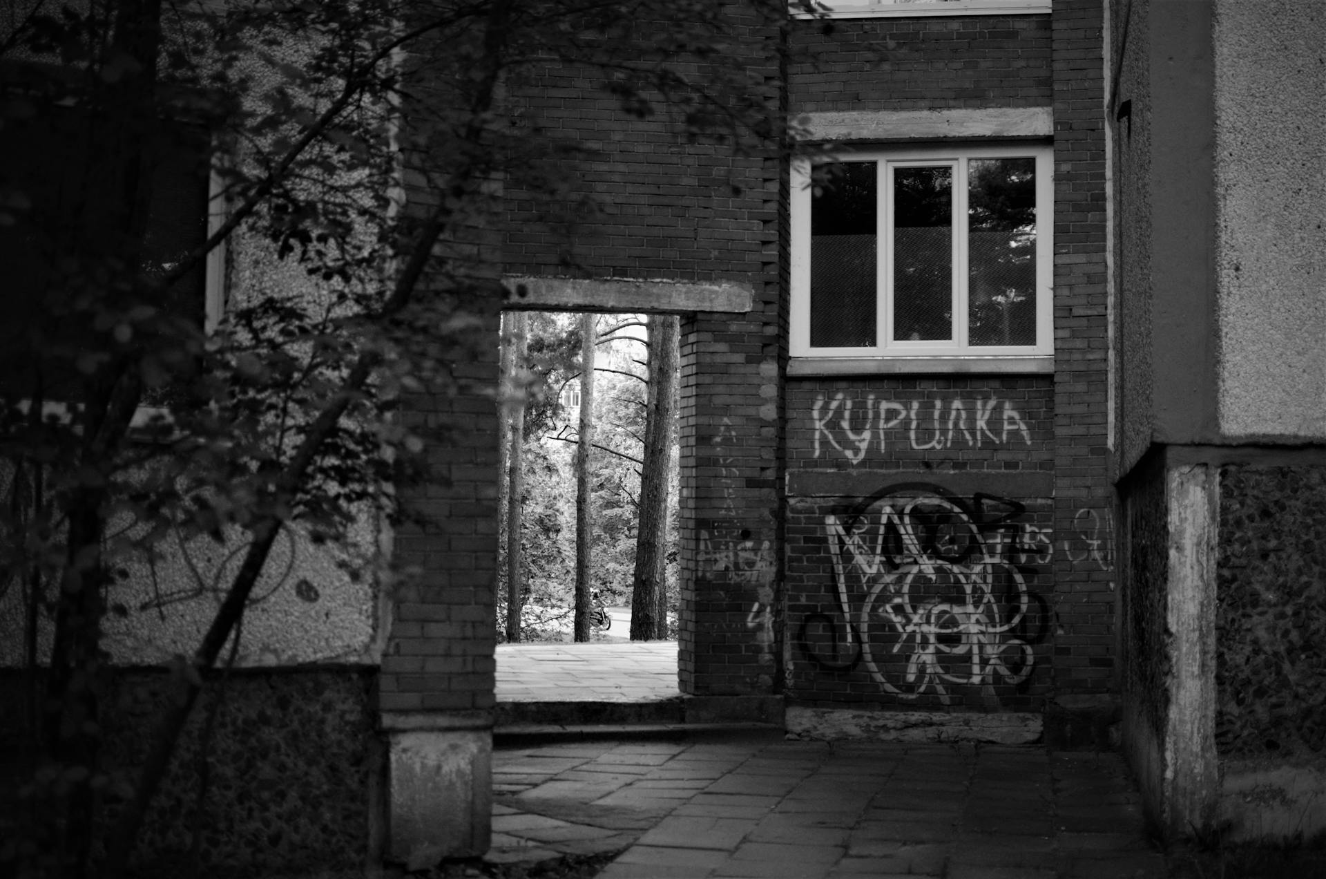 Grayscale Photo of a Old Buildings with Vandalized Wall