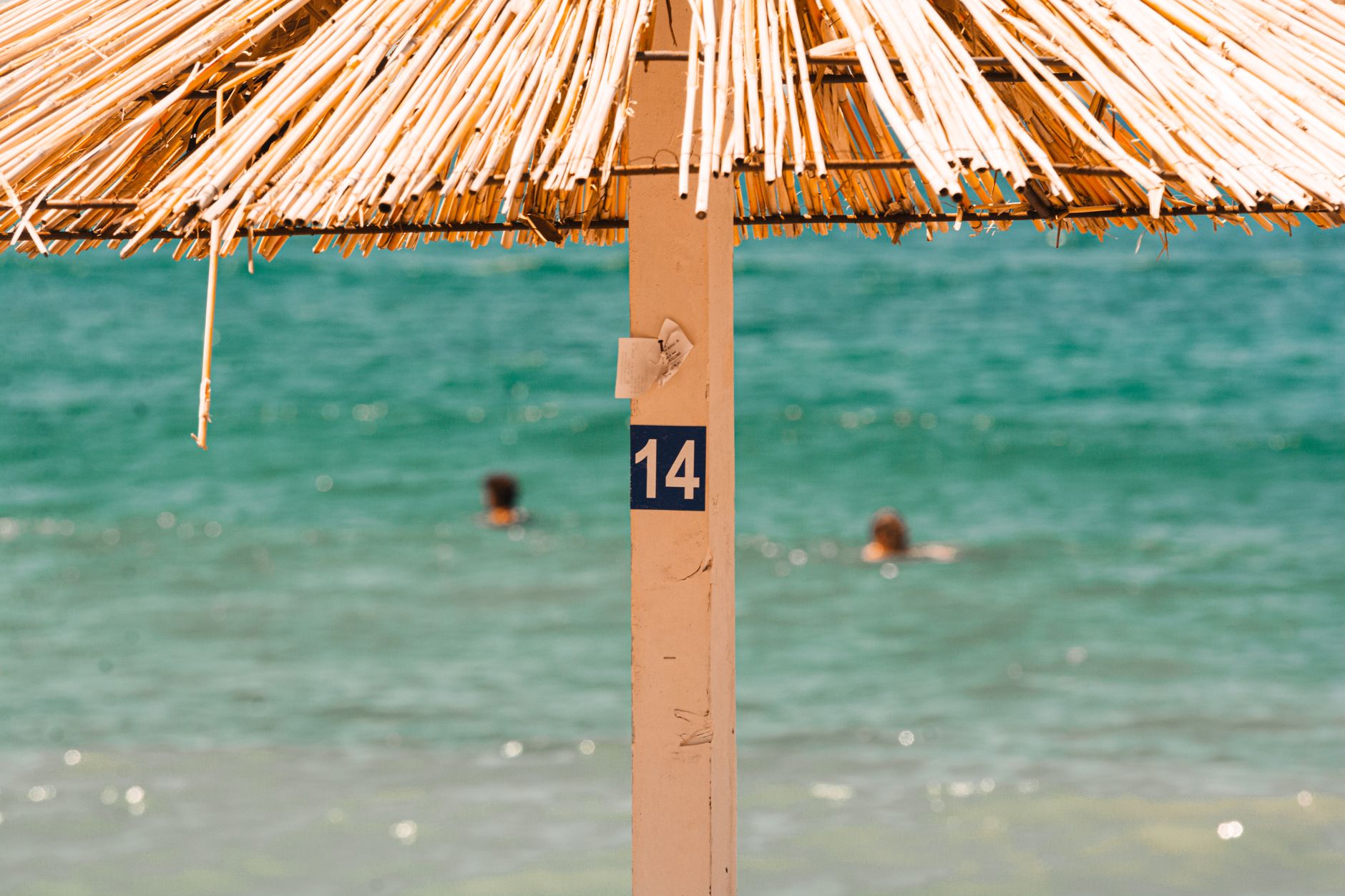 Close-up of a number 14 beach umbrella at a sunny Montenegro beach.