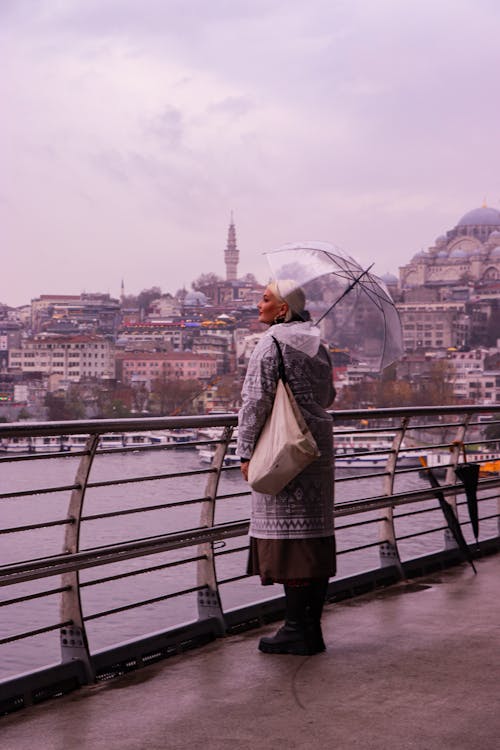 Woman Standing Beside Metal Fence Holding Umbrella