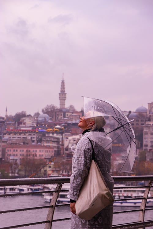 Woman Standing Beside Metal Fence Holding Umbrella