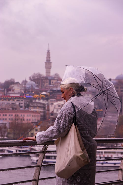 Woman Standing Beside Metal Fence Holding Umbrella
