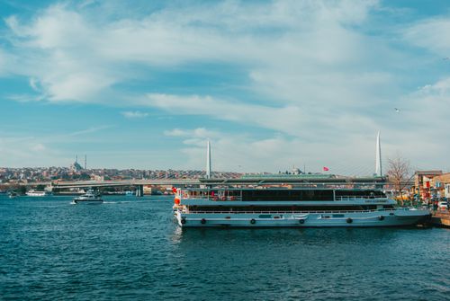 Free A tranquil scene of a ferry on the Bosphorus with view of Halic Bridge in Istanbul under blue skies. Stock Photo