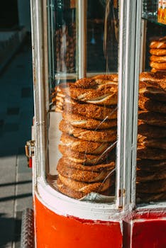 Close-up of sesame-covered simit bread stacked in a vibrant street food cart.