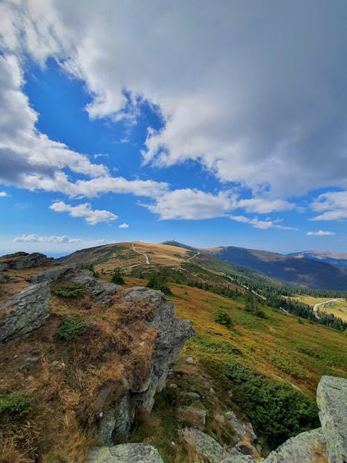 Landscape Scenery of Hills Under White Clouds and Blue Sky