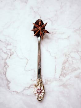 Elegant silver spoon with star anise on a marble background, perfect for decor.