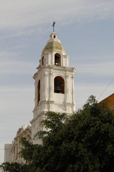 Elegant bell tower of a historic church in Puebla, Mexico, captured on a sunny day.