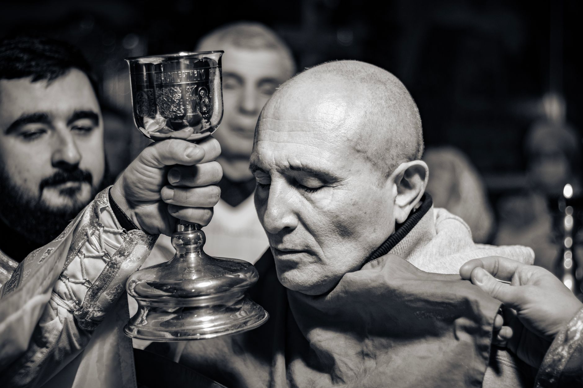 Intimate black and white portrait of a holy communion ritual in a church setting.