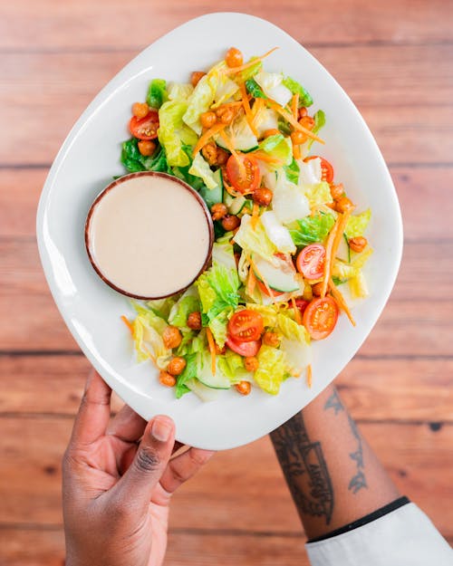 Free Hands Holding Plate with Salad and Dressing Stock Photo