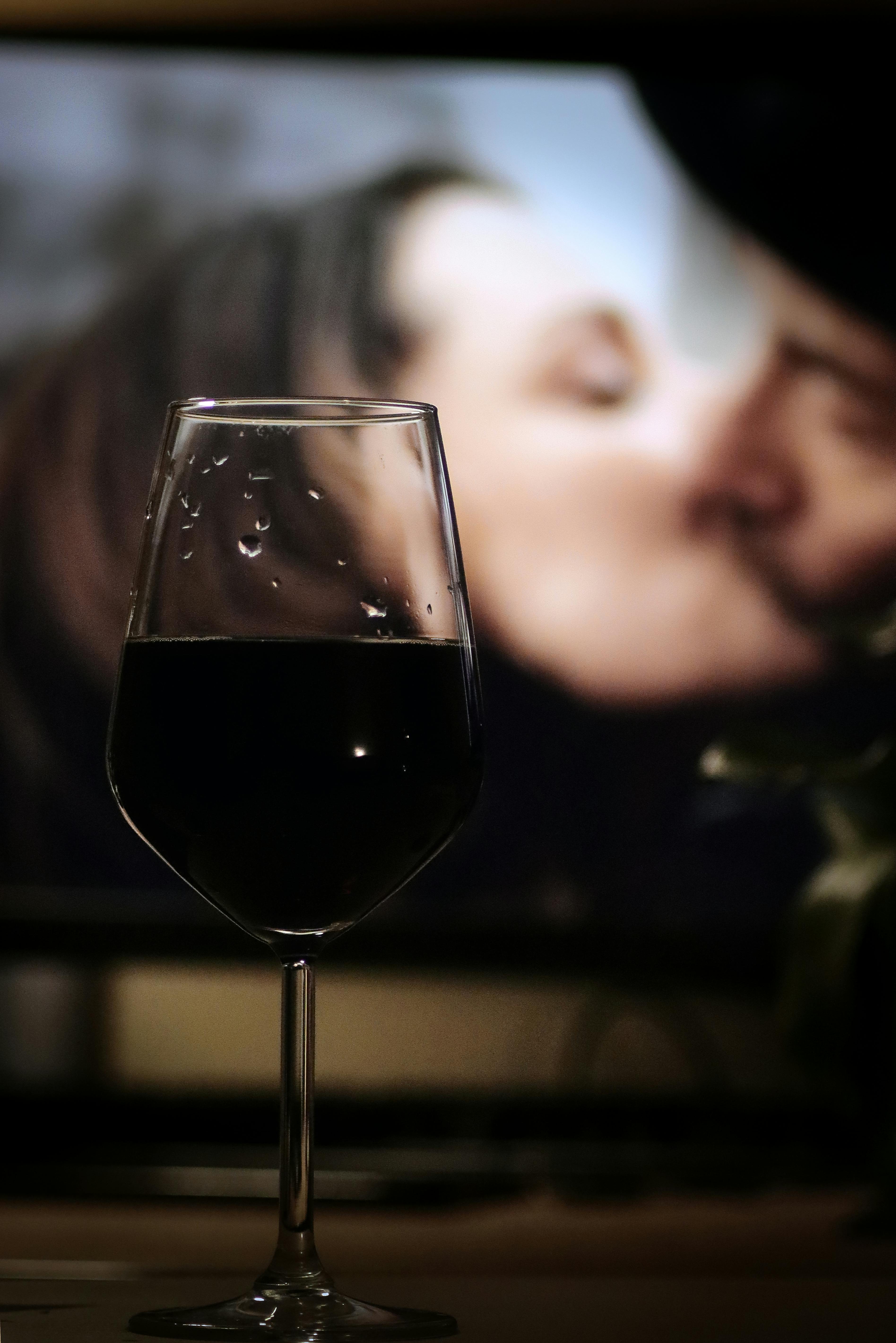 A glass of red wine with a romantic movie scene in the background.