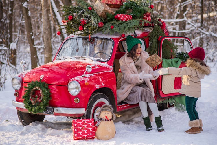 Mother And Daughter With Red Car With Christmas Tree On Top