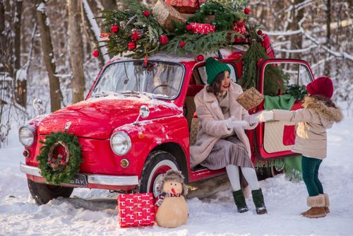 Free Mother and child enjoy winter with a decorated car and gifts in a snowy forest. Stock Photo