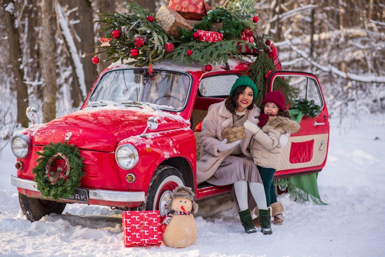 Mother And Daughter With Red Car With Christmas Tree On Top