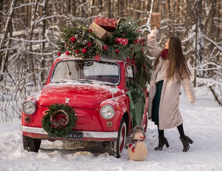 A woman decorates a vintage red car with Christmas gifts in a snowy forest.