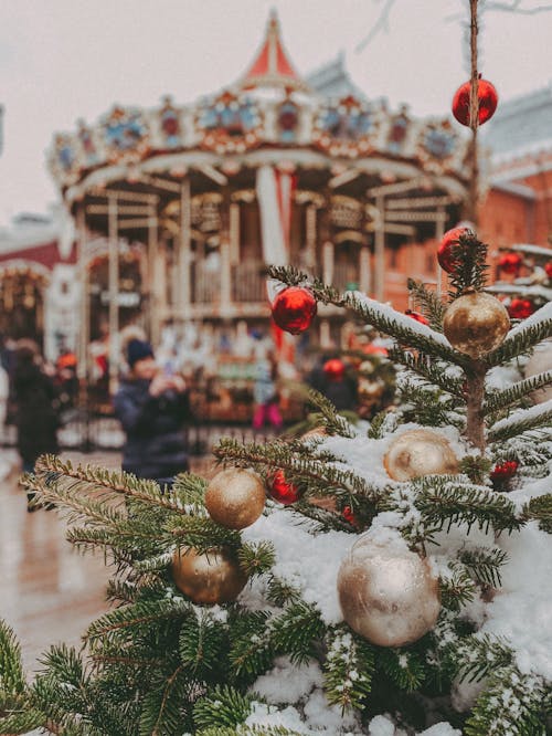 Christmas Tree With Hanging Christmas Ball Near Carousel  