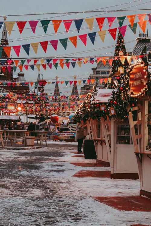 Free Vibrant Christmas market with festive decorations and colorful bunting in a snowy outdoor setting. Stock Photo