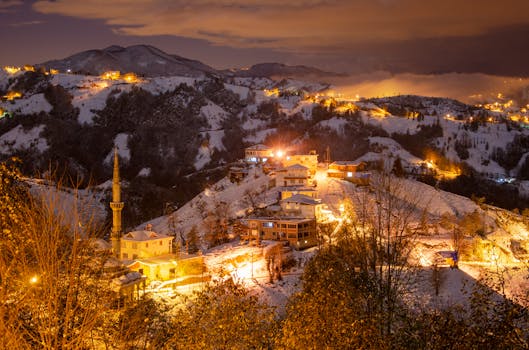 A serene snowy village with a mosque illuminated at twilight, capturing the essence of winter.