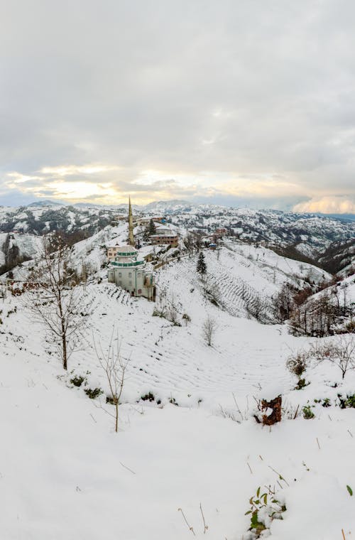 A White and Green Building on Snow Covered Mountain during Winter