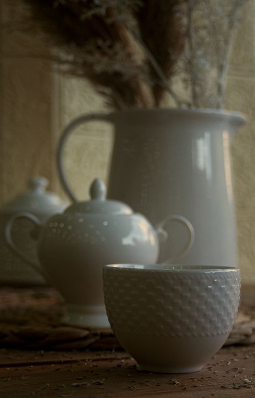 Free Sophisticated still life featuring a ceramic teacup and pitcher in a warm, moody setting. Stock Photo