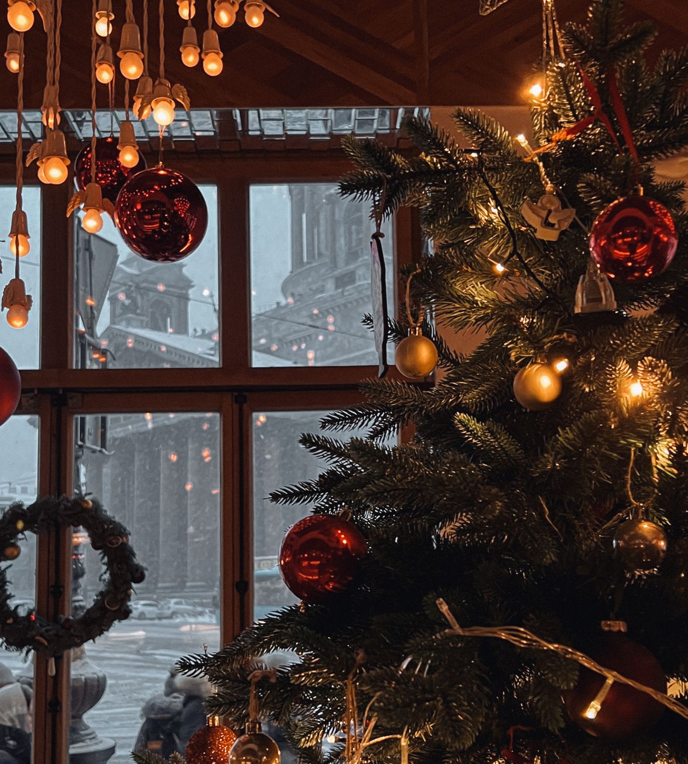 Illustrative apartment holiday scene with evergreen decoration, warm lights, and a snowy view through a window