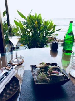 Luxurious table setting featuring fresh oysters, wine, and coastal view.