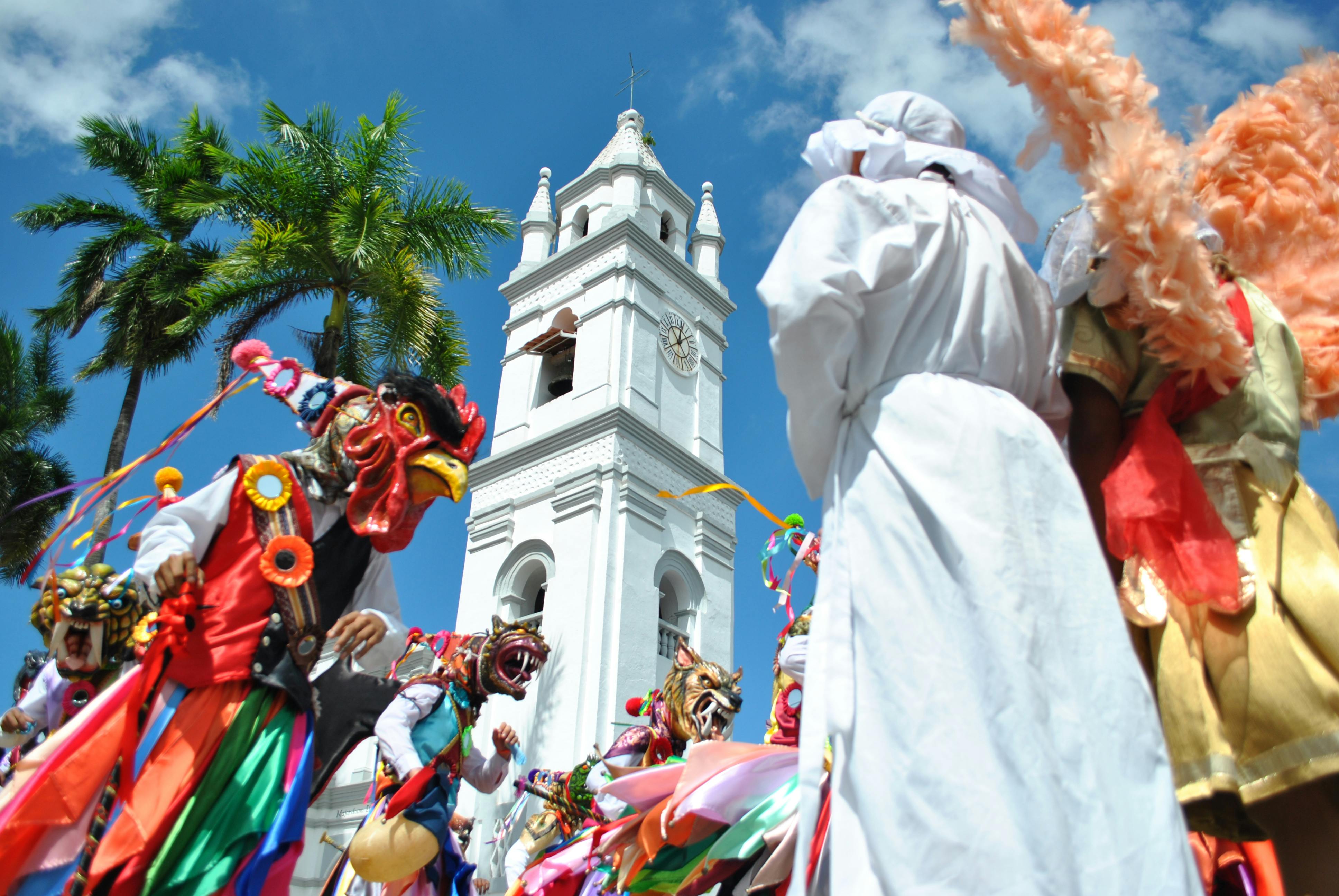 people in costumes parading near the church of san atanasio bell tower