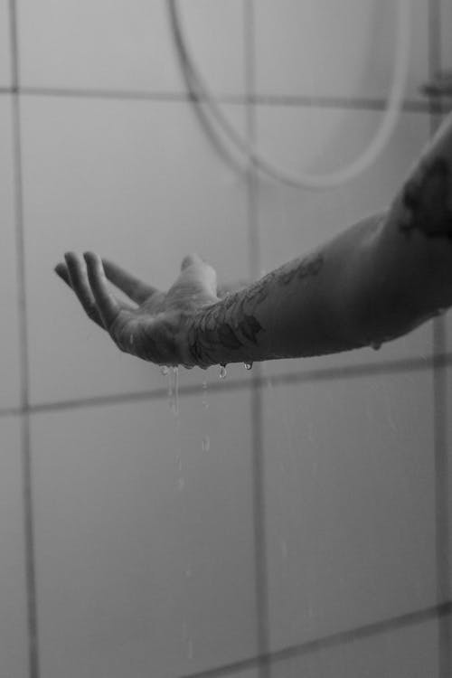 Grayscale Photo of Water Dripping from a Person's Arm