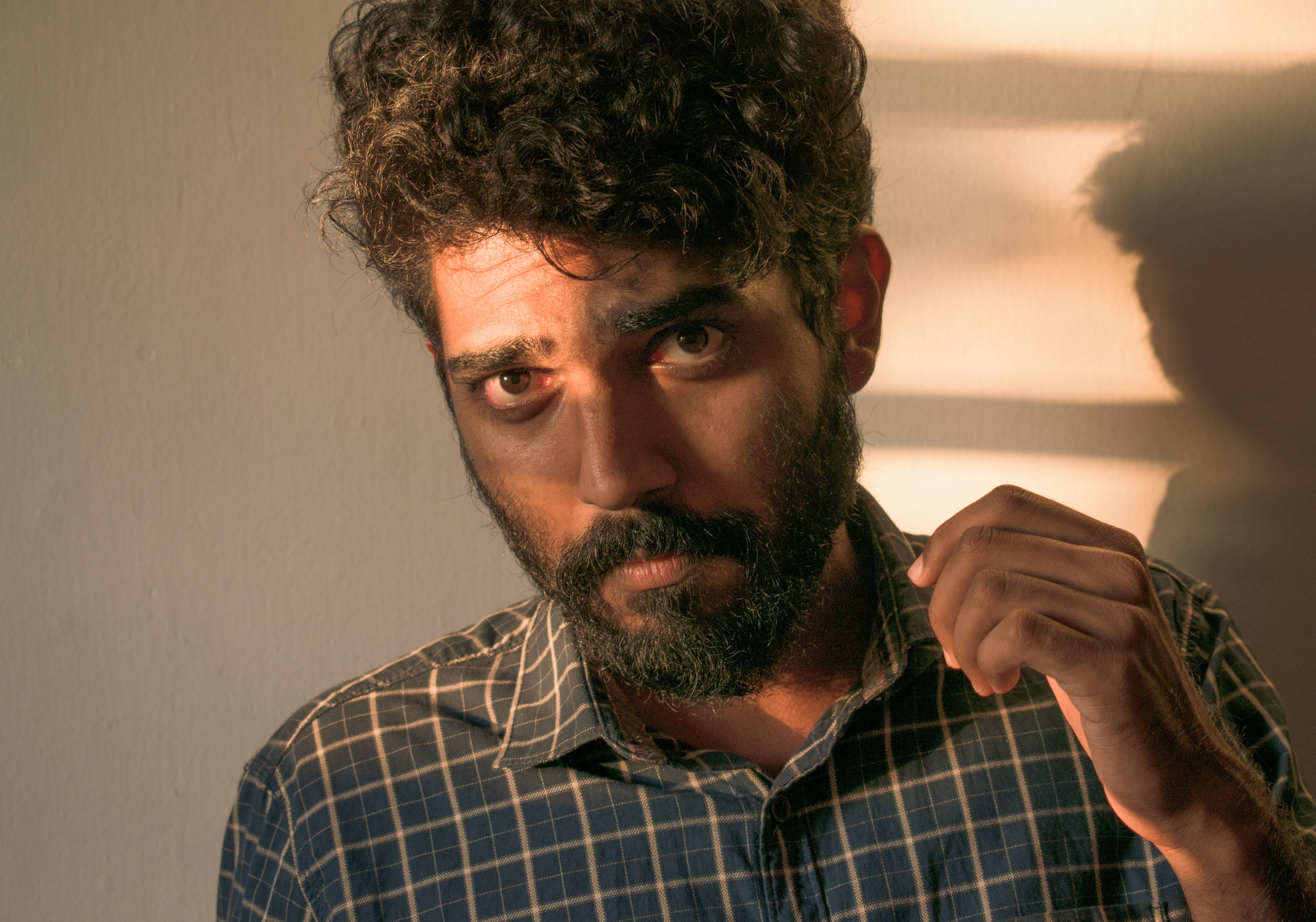 Portrait photograph of a bearded man wearing a plaid shirt with dramatic lighting and shadows.