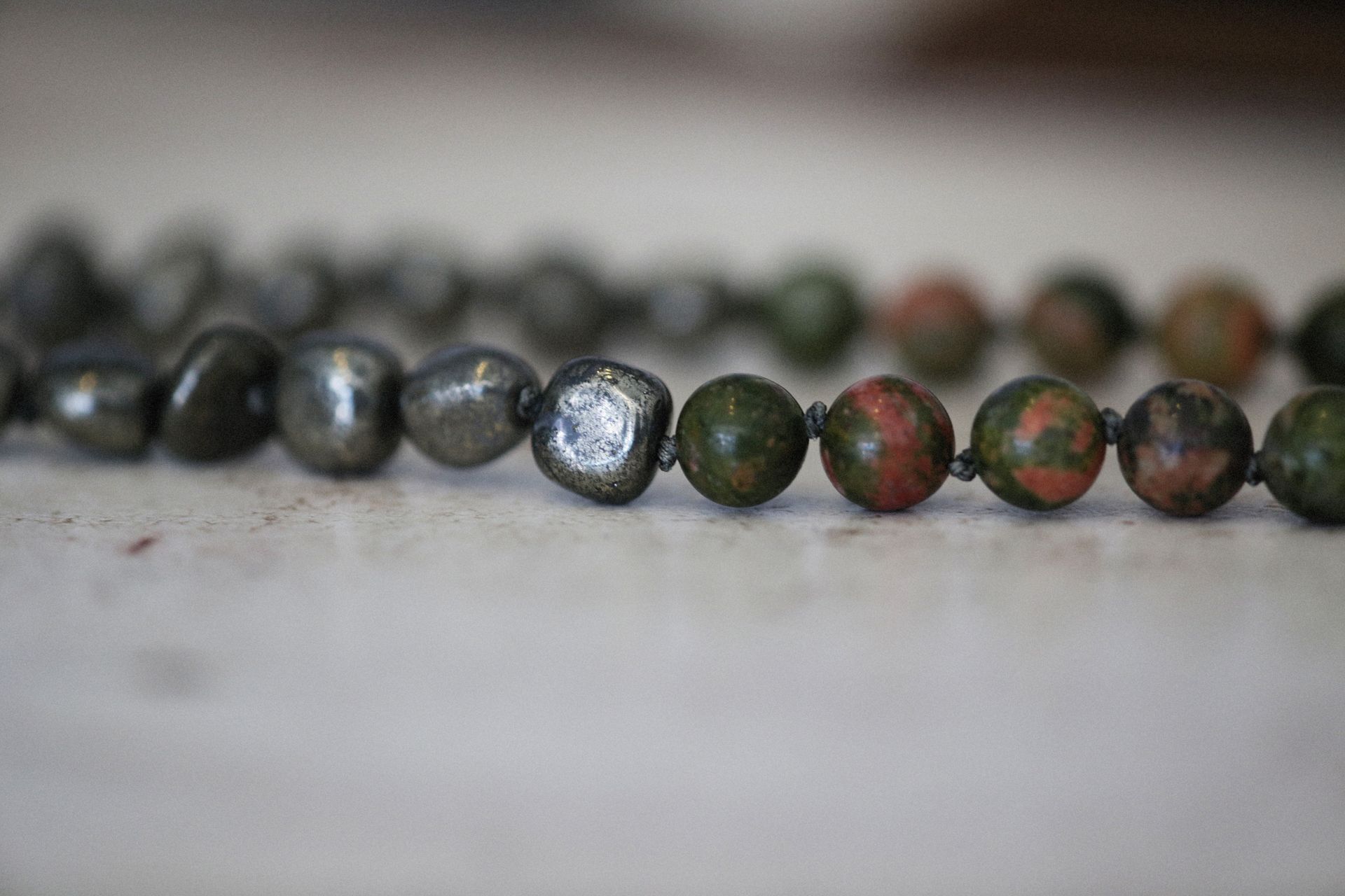 Artistic close-up of a bead necklace showcasing natural stones and intricate design in a still life setting.