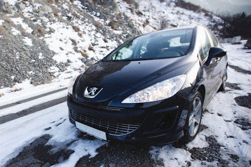 A Black Peugeot Car on Snow Covered Ground