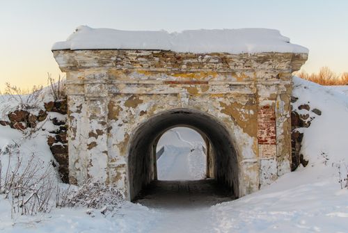 Free An old stone archway covered with snow in a serene winter countryside setting. Stock Photo